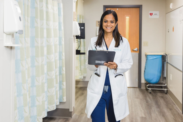 A female doctor in Atlanta, GA, holding a tablet in a hospital hallway
