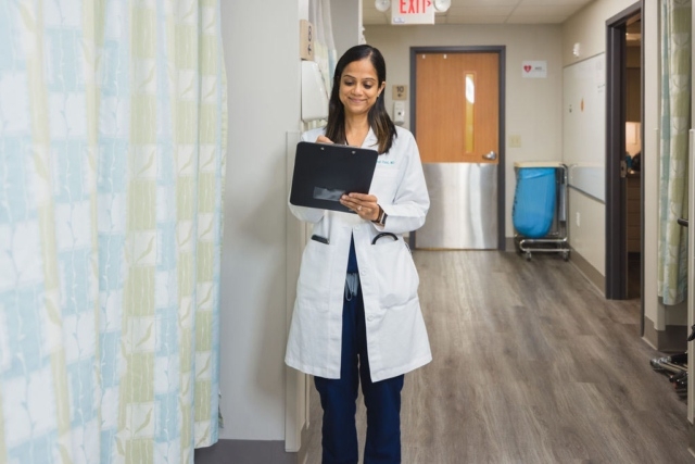Doctor reviewing a tablet while standing in a hospital hallway in Atlanta, GA