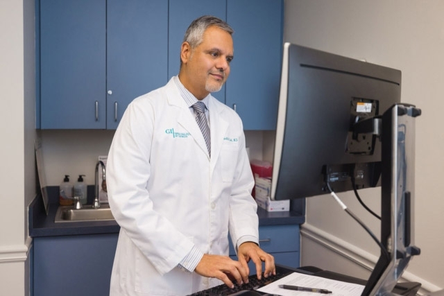 Doctor in a white lab coat working on a computer in a medical office in Atlanta, GA