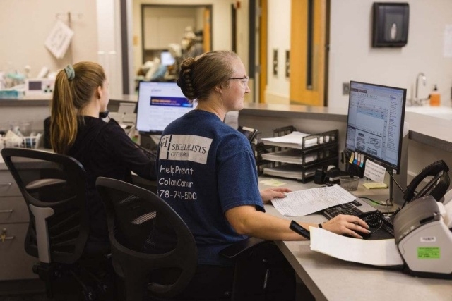 office-staff-working-at-computers GI Specialists of Georgia Staff Members Working at a Desk with Computers and Documents