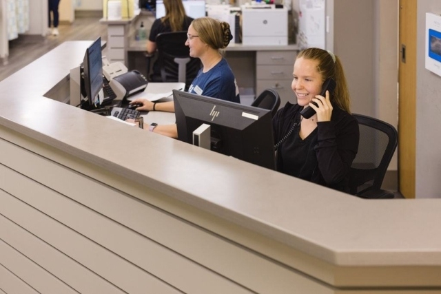 Reception desk with two people working on computers and answering phone calls in Atlanta, GA
