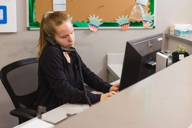 Receptionist sitting at a desk using a computer and talking on the phone in Atlanta, GA
