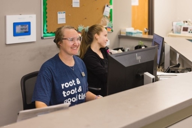 Two staff members are working at a reception desk with computers and office supplies in Atlanta, GA
