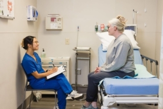 Healthcare professional taking notes while patient sits on exam bed in medical clinic in Atlanta, GA