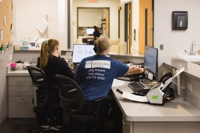 Staff working at a medical office desk with computers and administrative equipment in Atlanta, GA