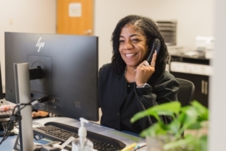 Office staff member at computer workstation speaking on phone in reception area in Atlanta, GA