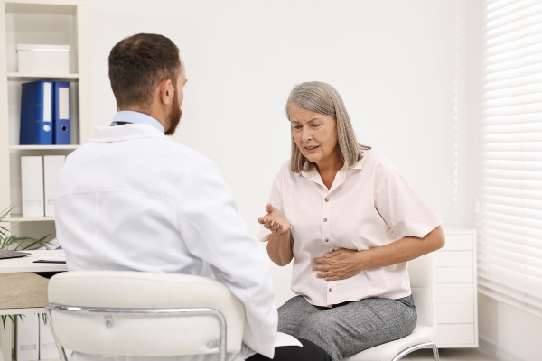 Doctor consulting senior patient with stomach pain